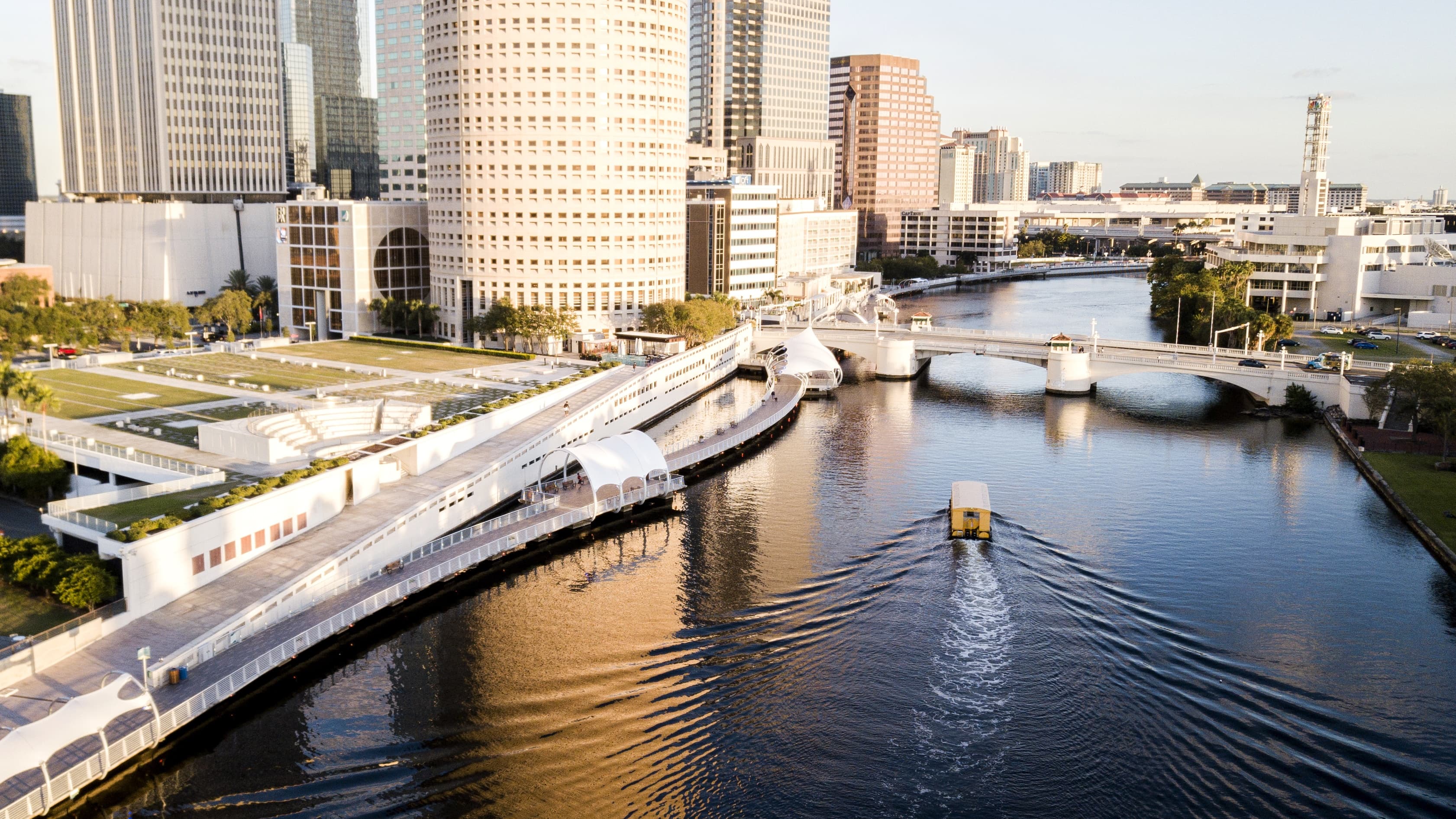 Tampa Riverwalk pedestrian waterfront path with downtown Tampa office buildings and glass towers in the background on a sunny day