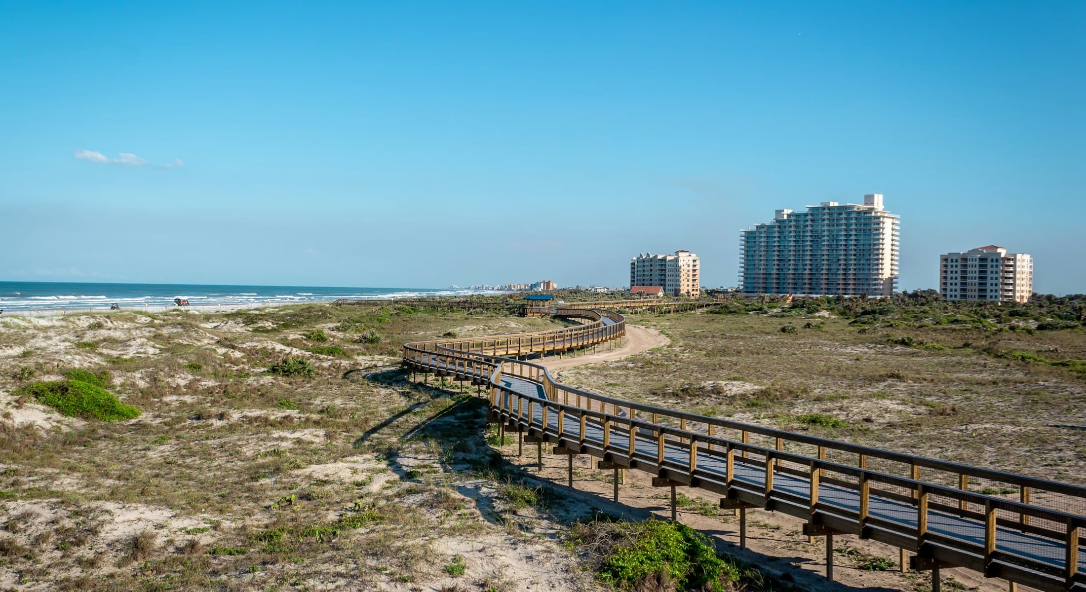 Boardwalk through the dunes at Smyrna Dunes Park with New Smyrna Beach condominiums and the Atlantic beyond