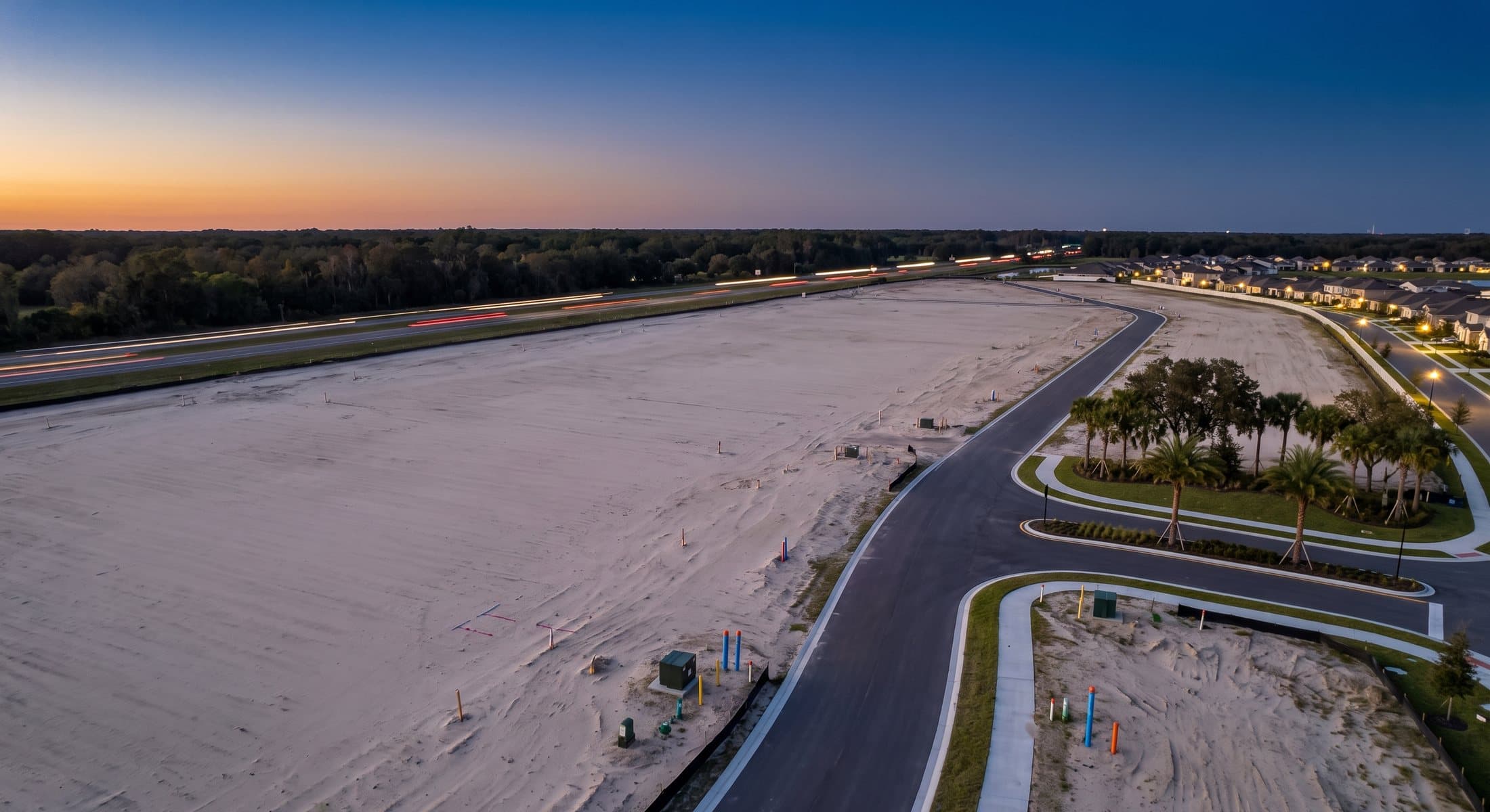 Aerial view of cleared vacant land beside a Florida highway at dusk — the kind of unwatched parcel deed fraud targets